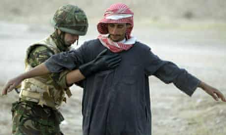 A British soldier stops and searches an Iraqi, at a checkpoint