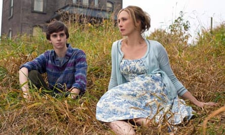 Vera Farmiga as Norma and Freddie Highmore as Norman Bates sitting on grass outside house