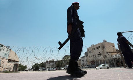 A police officer watches as razor wire is installed on the outskirts of Manama, Bahrain