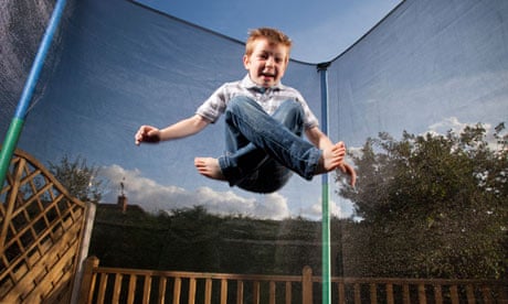 Young boy playing on a garden trampoline with a safety net around the edge