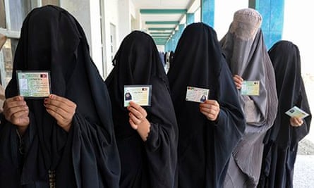 Burqa-clad women show ID cards as they wait to vote in Afghanistan's 2009 presidential elections