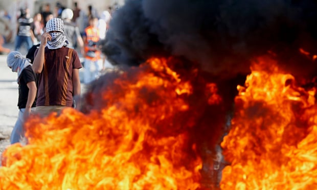 Palestinian protester stands near burning tyres during clashes with Israeli police in East Jerusalem