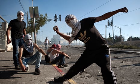 A Palestinian boy hurls stones to Israeli police during clashes in Shu'afat
