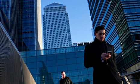 A worker looks at his phone at the Canary Wharf business district in London