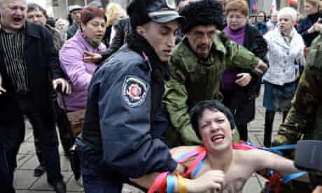 A police officer and pro-Russian demonstrators tussle with a topless Femen activist outside the Crim