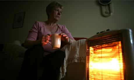 A pensioner sits with an electric heater, Conwy, Wales