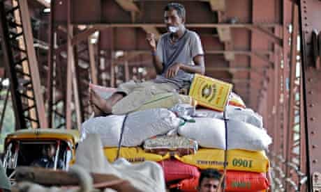 Worker sitting on a cart carrying rice sacks