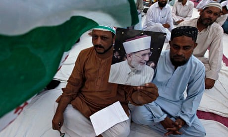 A supporter holds an image of Tahir-ul-Qadri, leader of Pakistan Awami Tehreek, at a gathering in re