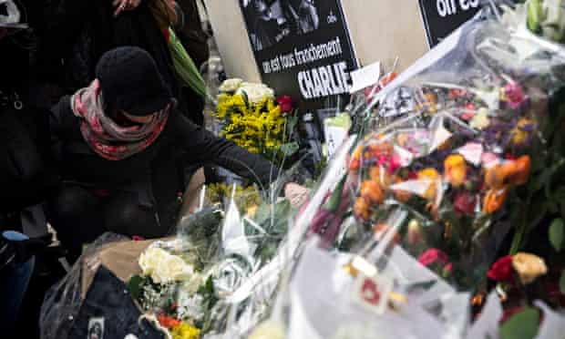 A woman adds her floral tribute outside the Charlie Hebdo headquarters