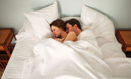 Couple lie in bed holding each other