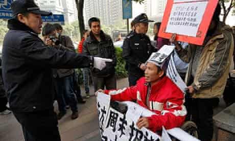 A policeman confronts a protester in a wheelchair outside the Southern Weekly newspaper in Guangzhou