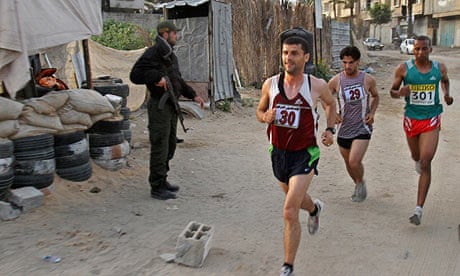 Palestinian runners pass a Hamas security officer in Beit Lahiya, Gaza, in the first Gaza marathon. 
