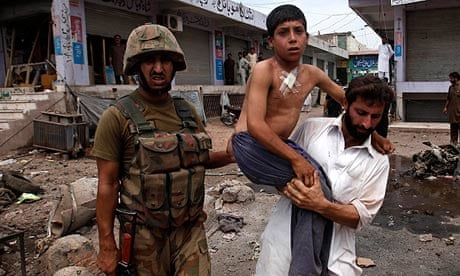 A security official carries a boy injured in a bomb attack in the outskirts of Peshawar