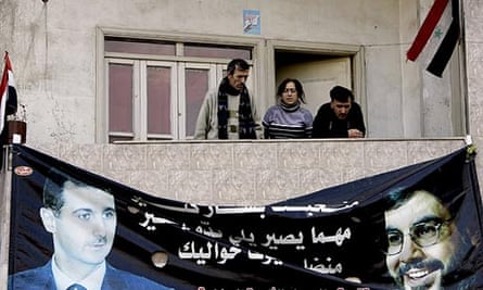 Syrians in Homs above a poster of Bashar al-Assad, left, and Hassan Nasrallah, leader of Hezbollah