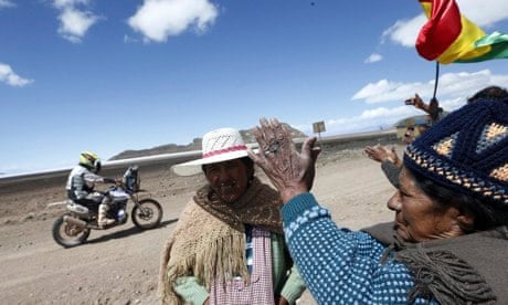 One of the participants in the Dakar rally passes indigenous people between Bolivia, and Chile