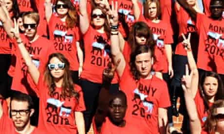A crowd of young people wearing Kony 2012 T-Shirts make the peace sign