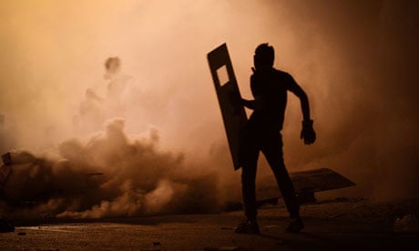 A Bahraini protestor stands amidst tear gas fired by riot police in Diraz