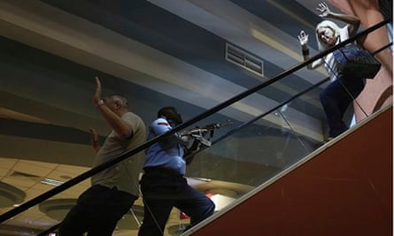A police officer secures an area as civilians flee inside Westgate Shopping Centre in Nairobi