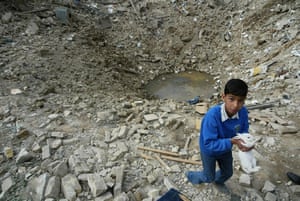 Great press photography: Bomb damage in the civilian neighourhood, a child recovers a rabbit