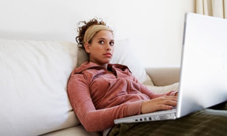 Teenage girl sitting on sofa, using laptop, looking away