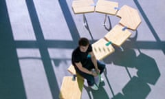Student sitting on row of school desks formed into a question mark symbol