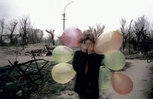 Europe 1945-2011: A girl festooned with balloons covers her eyes amid the ruins of Grozny