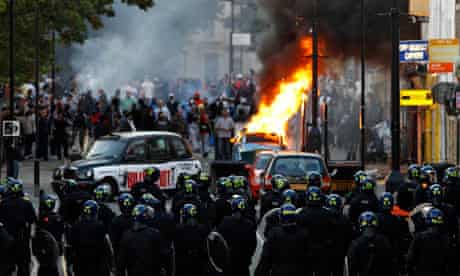 Riots: Police officers in riot gear block a road near a burning car in Hackney, east London