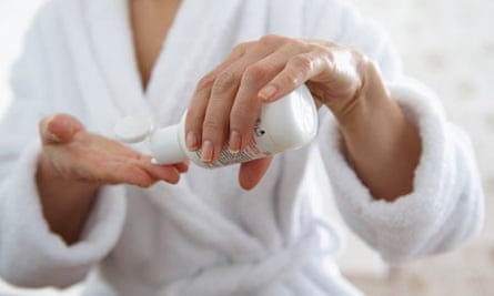 A mature woman applying moisturiser
