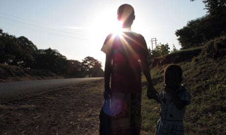 An eleven-year-old girl walks along a road with her sister in Tanzania