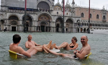 People sit at a table in flooded St Mark's Square in Venice, Italy