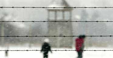People walk behind barbed wire at Auschwitz-Birkenau on January 27 2005, the 60th anniversary of the camp's liberation