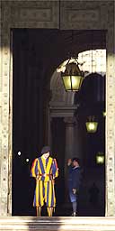 A Swiss guard looks down at the Vatican bronze door entrance
