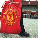 A young Man Utd fan takes home merchandise from Old Trafford. Fans are threatening to boycott club merchandise