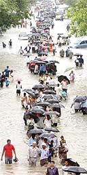 Indians walk down a flooded street after torrential rains paralysed Mumbai