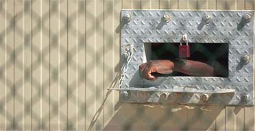 A detainee's arm hangs outside his cell at Camp Delta in Guantanamo Bay