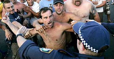 A man tries to hit police with a beer bottle at Cronulla Beach, Sydney