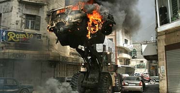 A bulldozer moves an Israeli army jeep set alight during clashes in Nablus