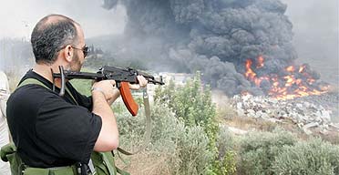 A Hizbullah gunman aims his AK47 at a fire caused by an explosion in Kfarshima, near Beirut, Lebanon