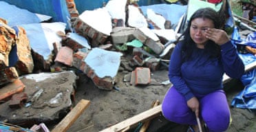 An Indonesian woman weeps as she sits amid the rubble of her house in Pangandaran, Java.