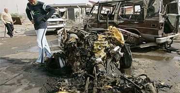 A man looks at the wreckage of a vehicle used in a car bomb attack in Baghdad
