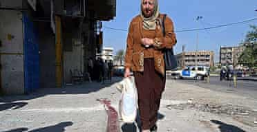 An Iraqi woman walks along a smeared blood trace left by a wounded victim near an explosion site in Baghdad, Iraq. 