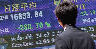A Japanese businessman looks at the early morning stock figures on a NIkkei stock market screen in downtown Tokyo.