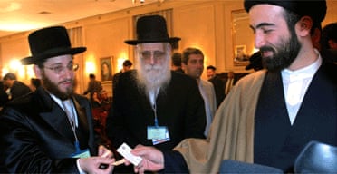 Rabbi Moishe Arye Friedman, left, from Austria, give his business card to a Muslim clergyman, as Rabbi Ahron Cohen from England, looks on, at the Holocaust conference in Tehran, Iran