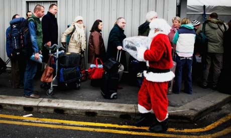 A man dressed as Santa Claus hands blankets to queueing passengers at Heathrow airport. Photograph: Daniel Berehulak/Getty