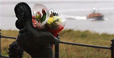 Flowers on a seaman's statue pay tribute to the victims of the helicopter crash in the Irish Sea