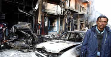 An Iraqi man stands at the scene of a triple car bombing in a Shia area of Baghdad on December 30