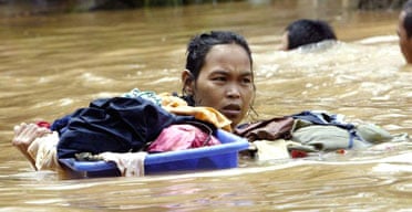 An Indonesian woman struggles through floodwaters with her belongings in Jakarta