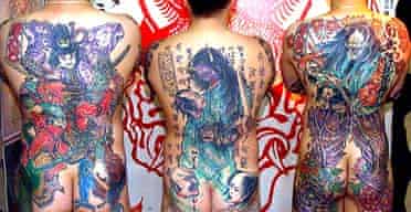 Three men show off their tattoos, heavily associated with Japanese gangsters, or yakuza