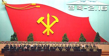 Delegates at a ceremony to mark the 65th birthday of Kim Jong Il, with a giant flag of North Korea's ruling Korean Workers' party in the background.