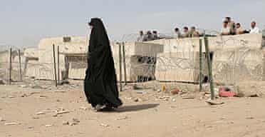 A woman walks past concrete blocks on the outskirts of the Shia enclave of Sadr City in Baghdad.